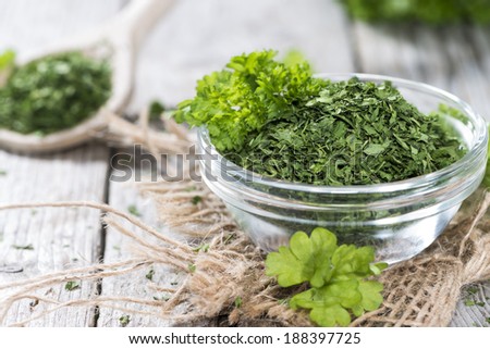 Small bowl with dried Parsley on vintage wooden background