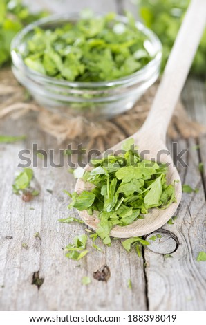 Fresh flat leaf Parsley (close-up shot) on weathered wooden background