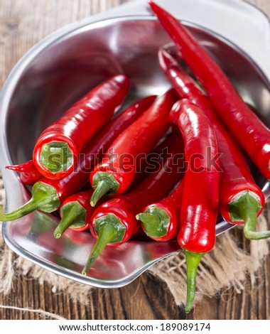 Small bowl with red Chillies on wooden background