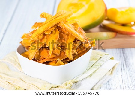 Small bowl with dried Mango slices and some fresh fruits