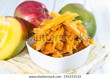 Small bowl with dried Mango slices and some fresh fruits