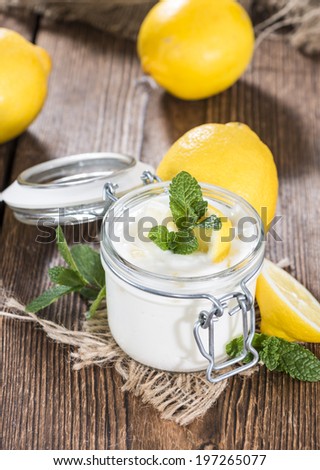 Portion of fresh homemade Lemon Yoghurt on wooden background (with some fresh Mint)