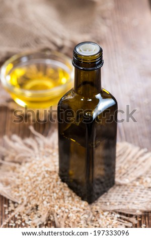 Small bottle with Sesame Oil and some Seeds on wooden background