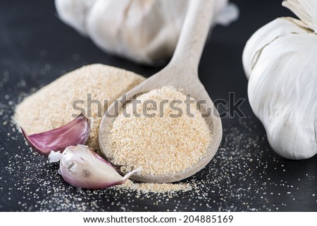 Wooden Spoon with Garlic Powder on dark background