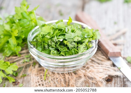 Heap of fresh cutted flat leaf Parsley (on wooden background)