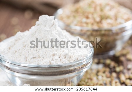 Buckwheat Flour with some grains on dark wooden background