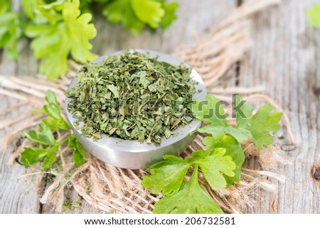 Portion of dried flat leaf Parsley on wooden background