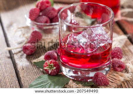 Homemade Raspberry Liqueur with fresh fruits on wooden background