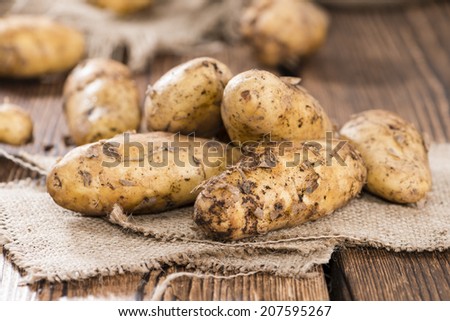 Heap of freh Potatoes on wooden background (close-up shot)
