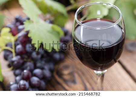 Glass with Red Wine and fresh Grapes on wooden background