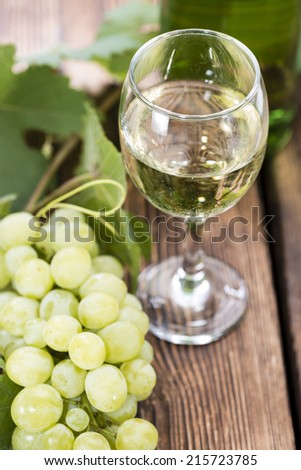 White Wine in a glass with fresh grapes (on wooden background)