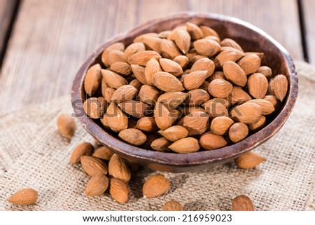 Bowl with Almonds on rustig wooden background (close-up shot)