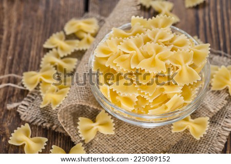 Portion of Raw Farfalle (also known as Bow-Tie Pasta) on wooden background