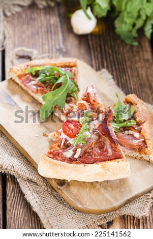 Fresh made Ham Pizza with rocket, tomatoes, garlic and cheese on wooden background