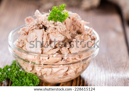 Canned tuna with fresh parsley (detailed close-up shot) on wooden background