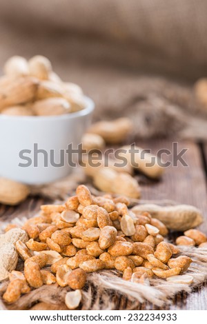 Roasted Peanuts with spices and salt (close-up shot) on dark wooden background