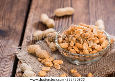 Roasted Peanuts with spices and salt (close-up shot) on dark wooden background