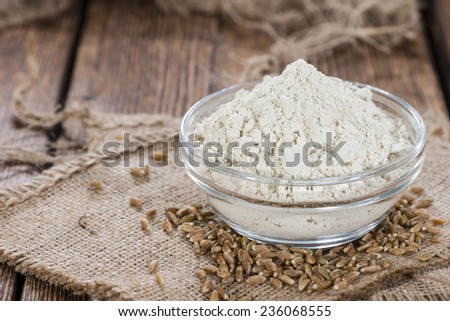 Small bowl with Spelt Flour and whole seeds on wooden background