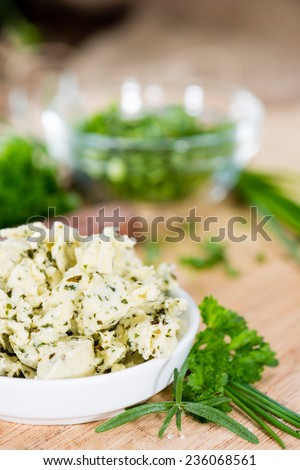 Portion of Herb Butter (with Chives, Basil, Oregano, Parsley and Rosemary) on rustic wooden background