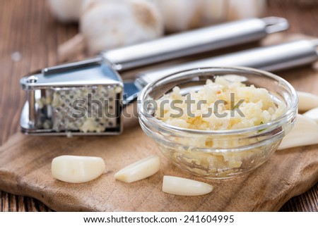Portion of Crushed Garlic (close-up shot) on wooden background