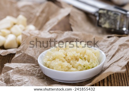 Portion of Crushed Garlic (close-up shot) on wooden background