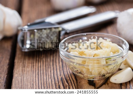 Fresh pressed Garlic (detailed close-up shot) on rustic wooden background