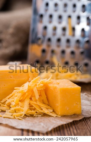 Portion of grated Cheddar Cheese on rustic wooden background