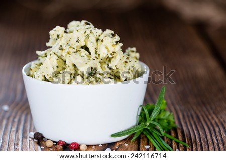 Portion of Herb Butter (with Chives, Basil, Oregano, Parsley and Rosemary) on rustic wooden background