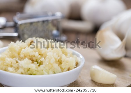 Crushed Garlic (close-up shot) on rustic wooden background