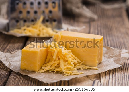Cheddar Cheese (grated) as close-up shot on an old vintage wooden table