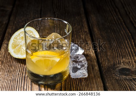 Glass with Whiskey Sour and ice cubes (close-up shot)