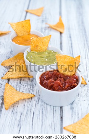 Nacho Dips (Salsa, Guacamole and Cheese) on wooden background