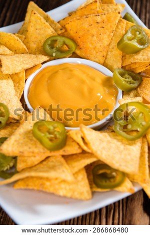 Portion of Nachos (with Cheese Dip) on an old wooden table