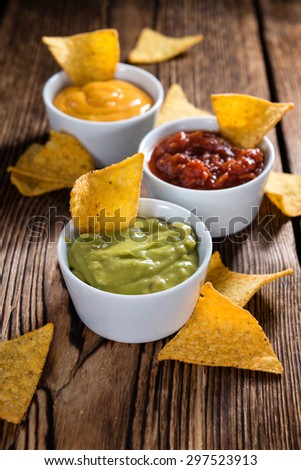 Three different nacho dips (Salsa, Cheese and Guacamole)