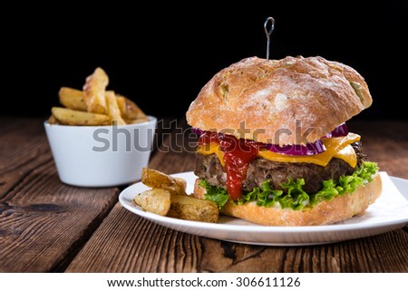 Fresh made Ciabatta Burger with chips on vintage wooden background
