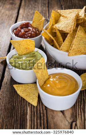 Three different nacho dips (Salsa, Cheese and Guacamole)