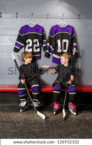 Two young boys fist pump before hockey game in dressing room