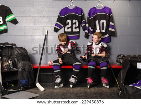 Two Boys Get Dressed in hockey gear in dressing room before game