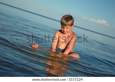 A young boy plays in calm water, evening light