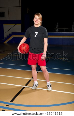 A female teenage basketball player in school gymnasium.
