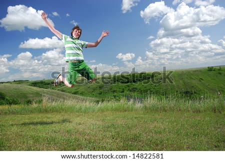 A young man jumps for joy at edge of prairie coulee.
