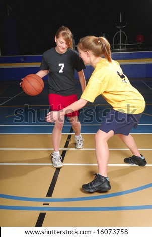 Two female basketball players compete in gym