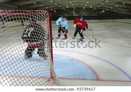 Young Boys Playing Hockey in front of the Goalie Net