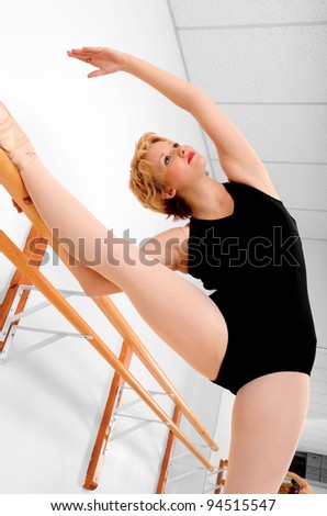 A Ballerina Stretches at the Ballet Barre