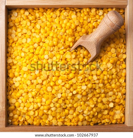 wooden box full of yellow split lentils with scoop