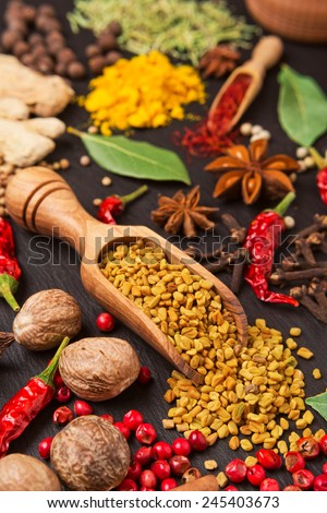 still life with different spices and herbs over black background