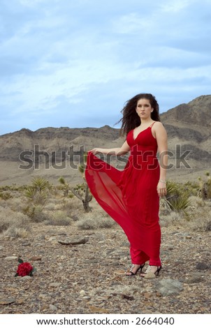 A girl wearing a red evening gown in the desert
