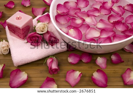 Fresh bright pink roses, petals, candle, and towel in a spa
