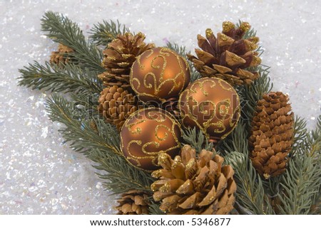 Christmas tree branch with pine cones, ornaments and snow