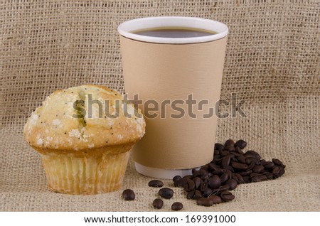 Coffee cup and lemon poppy seed muffin on jute background.